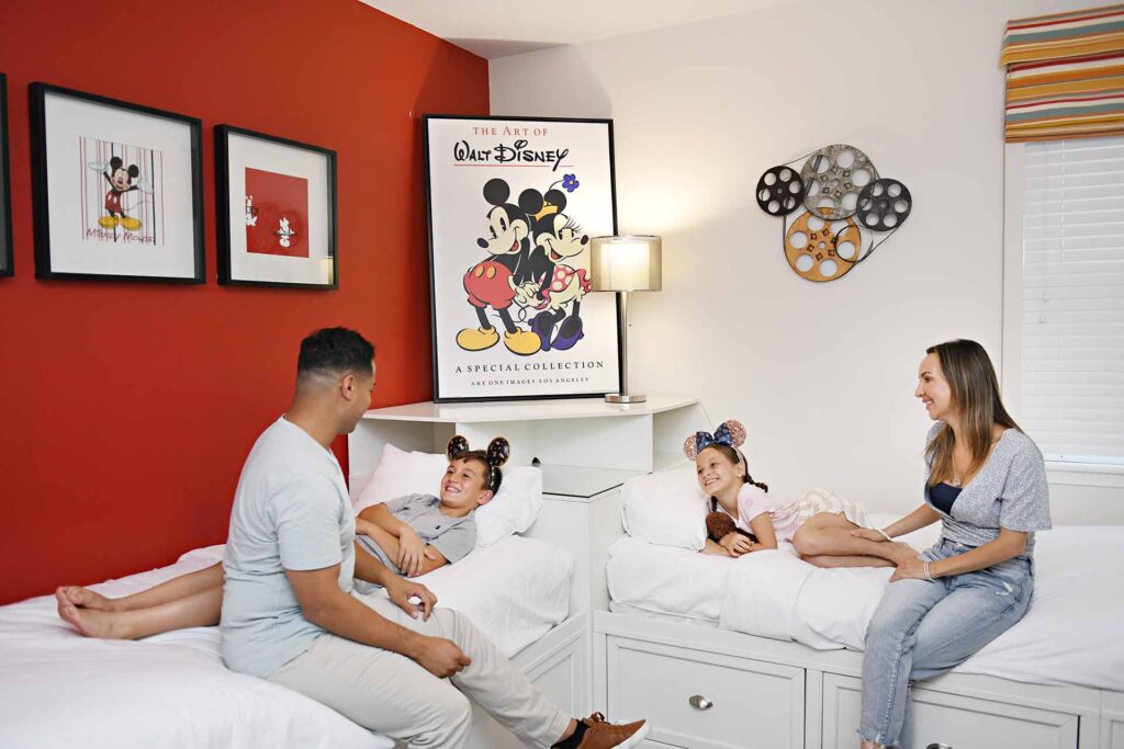 Родители укладывают детей спать в комнате, оформленной в стиле Диснея. Encore Курортный дом.