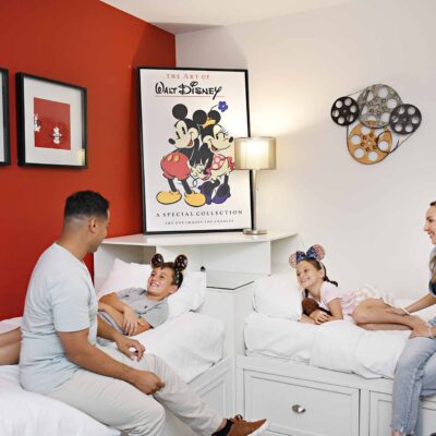 Parents tucking kids into bed in a Disney themed room at their Encore Resort home.