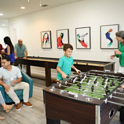 Large family playing on various game tables and arcade games in their Encore Resort home game room