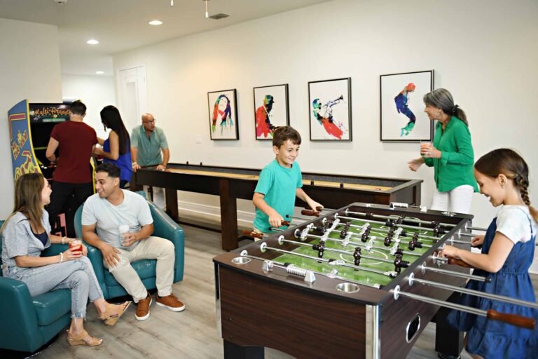 Large family playing on various game tables and arcade games in their Encore Resort home game room