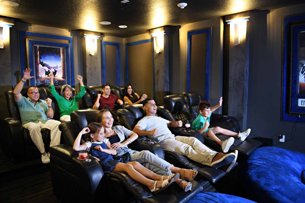 عائلة كبيرة تشاهد شيئًا مثيرًا في منزلهم Encore غرفة السينما المنزلية بالمنتجع.